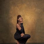Elegant portrait of a woman in black dress against a textured backdrop, conveying poise and sophistication.